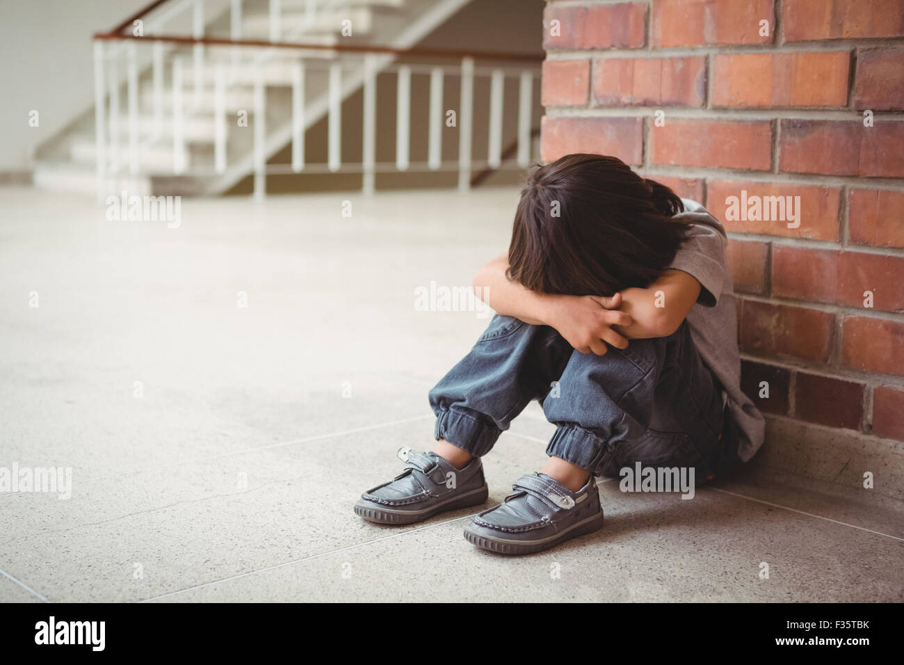 Sconvolto lonely bambino seduto da se stesso Foto Stock