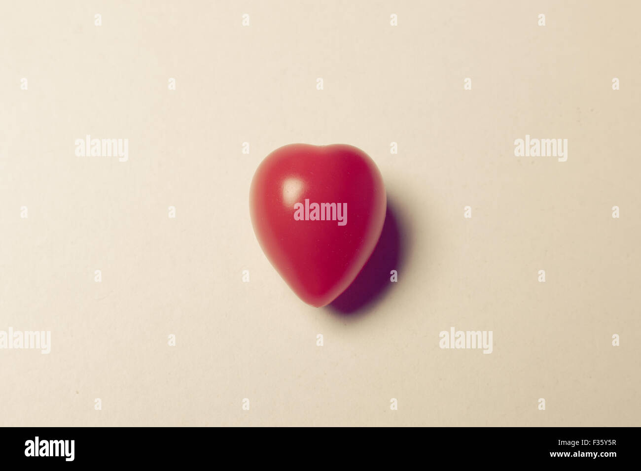 Insolito a forma di cuore di pomodori ciliegia su uno sfondo semplice Foto Stock