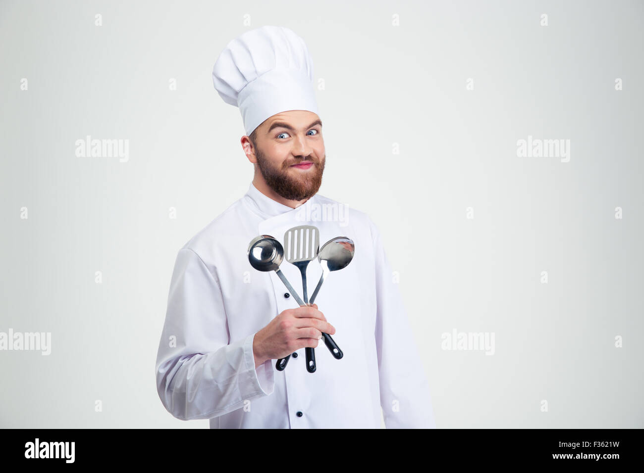 Ritratto di un maschio divertenti chef di cucina azienda cucchiai isolato su uno sfondo bianco Foto Stock