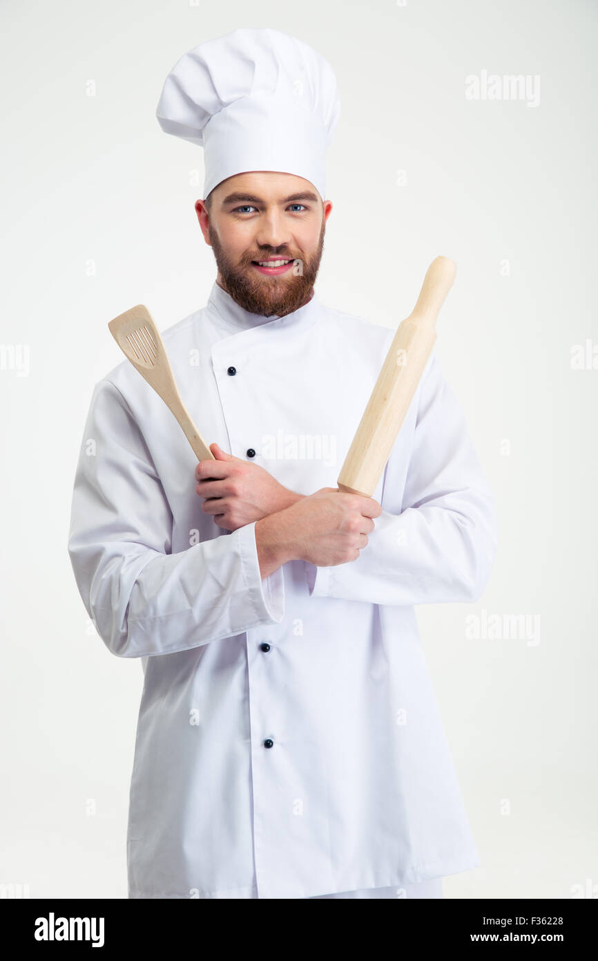 Ritratto di un bel maschio di chef di cucina tenendo un matterello e cucchiaio isolato su uno sfondo bianco Foto Stock