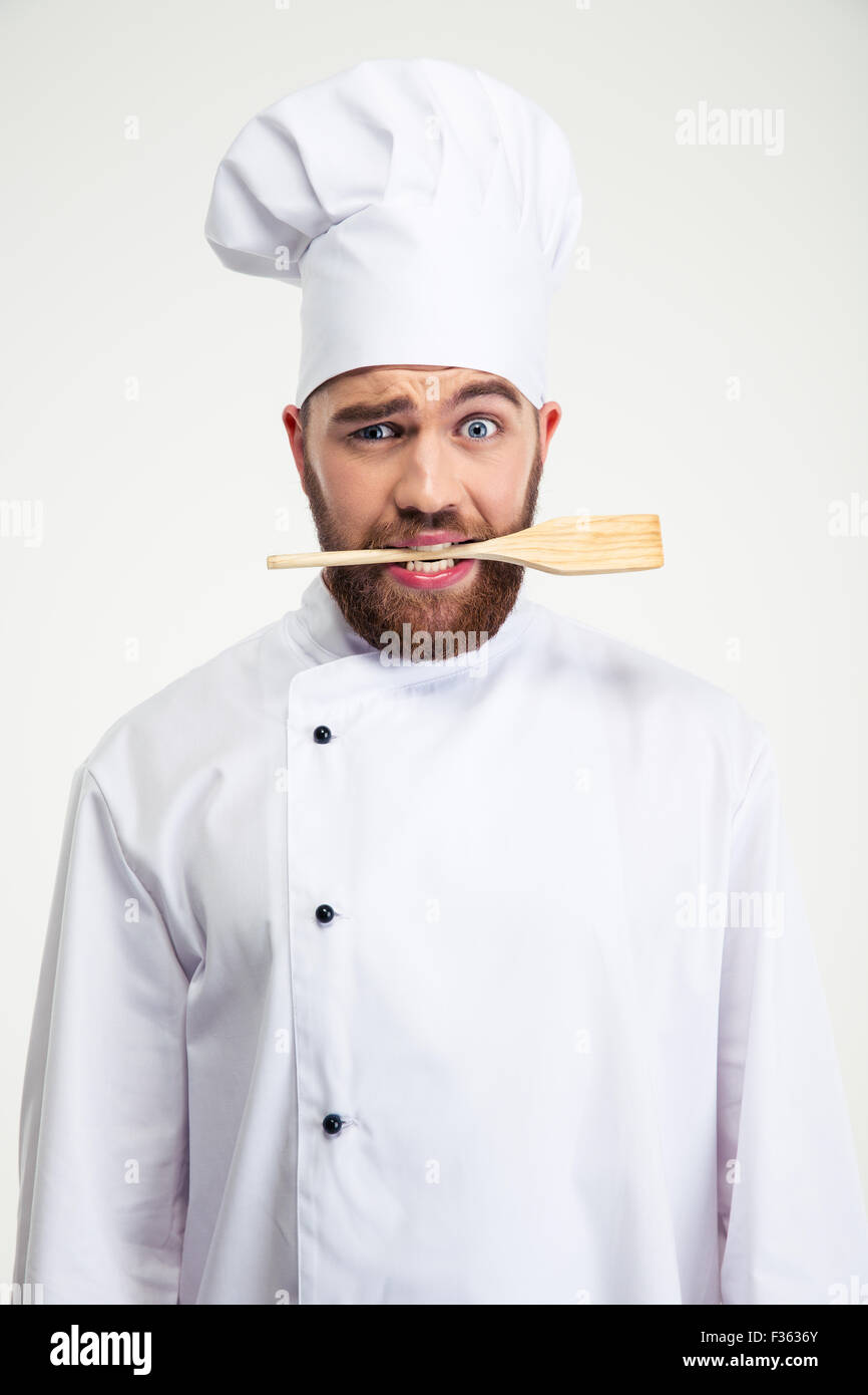 Ritratto di un bel maschio di chef di cucina azienda cucchiaio in denti isolati su sfondo bianco Foto Stock