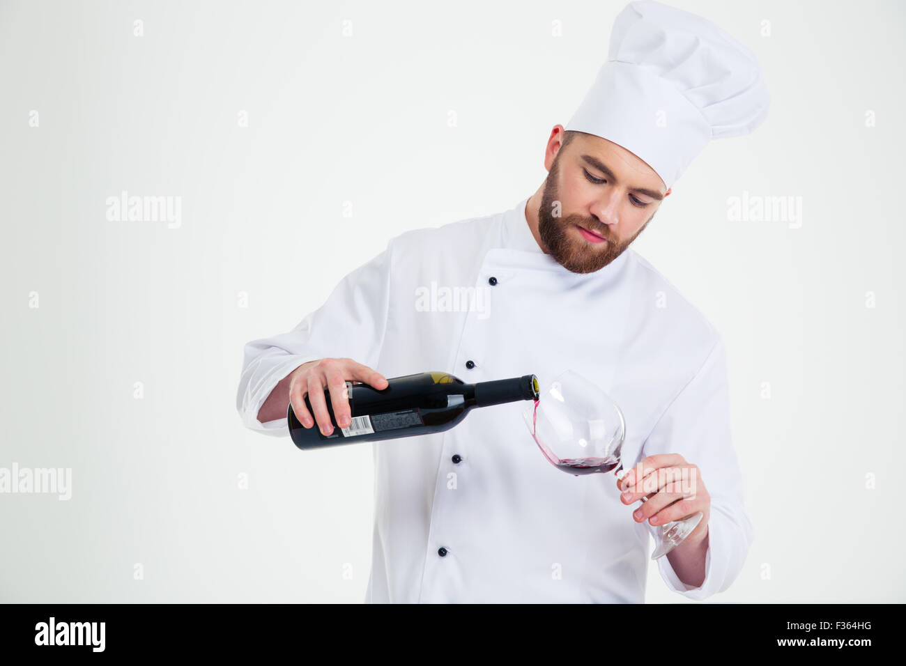 Ritratto di un maschio di chef di cucina versando il vino in wineglass isolato su uno sfondo bianco Foto Stock