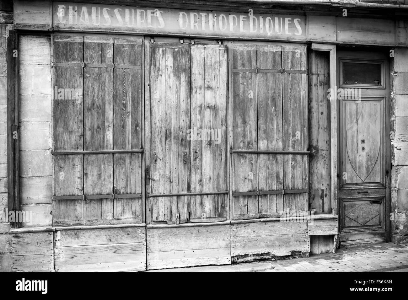 Un vecchio francese in disuso negozio di scarpe con persiane in B&W Foto Stock