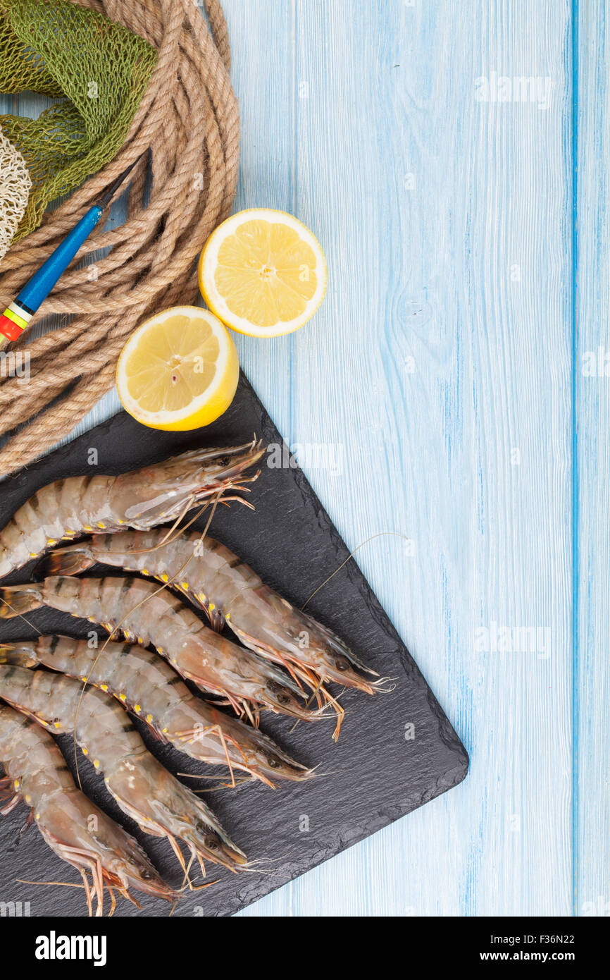 Crudo fresco gamberoni e attrezzature per la pesca su un tavolo di legno. Vista da sopra con lo spazio di copia Foto Stock