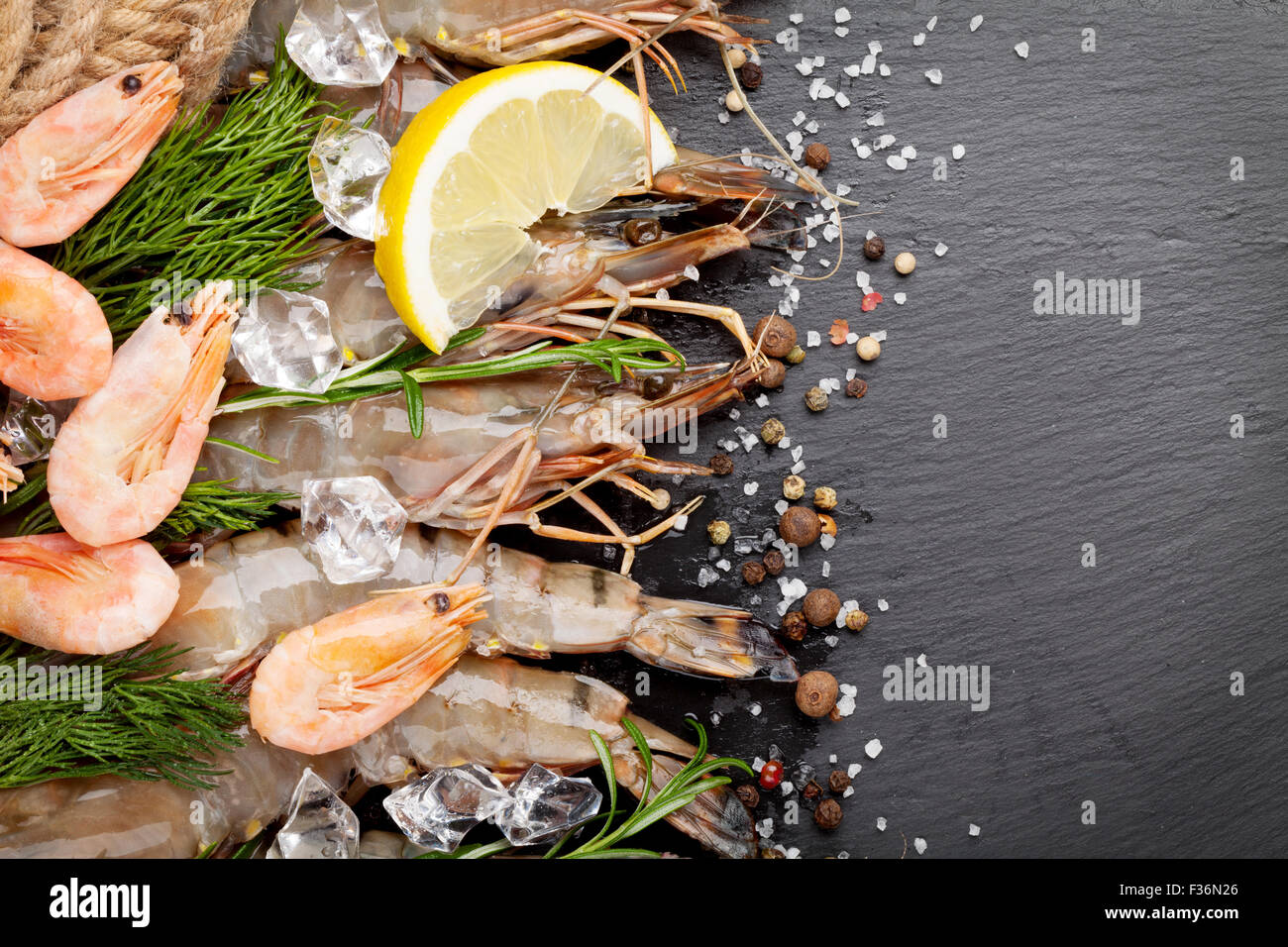 Gamberetti freschi con spezie sulla pietra nera dello sfondo. Vista da sopra con lo spazio di copia Foto Stock