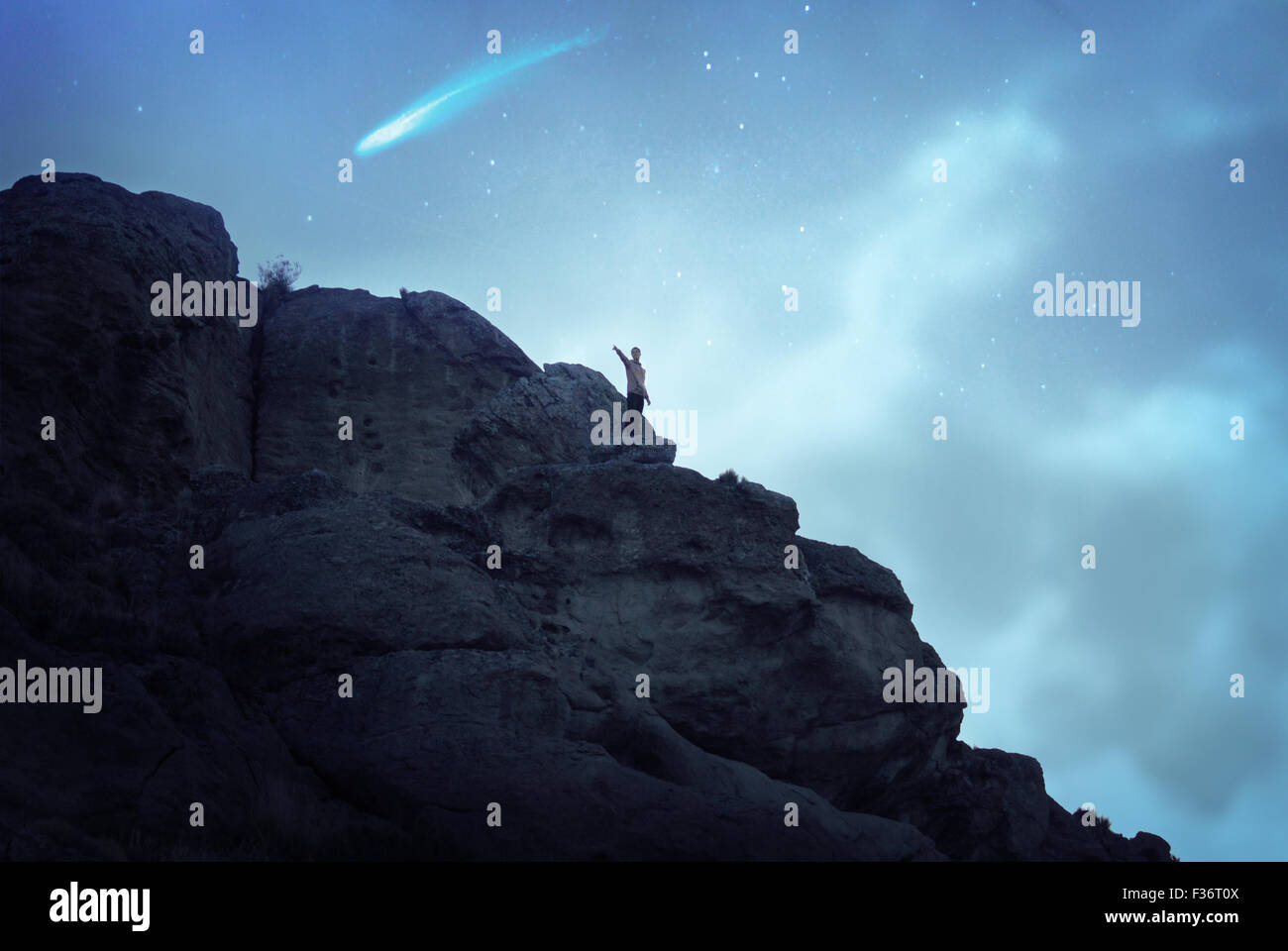 Ragazzo di arrampicata in una grande montagna sotto un cielo pieno di stelle Foto Stock