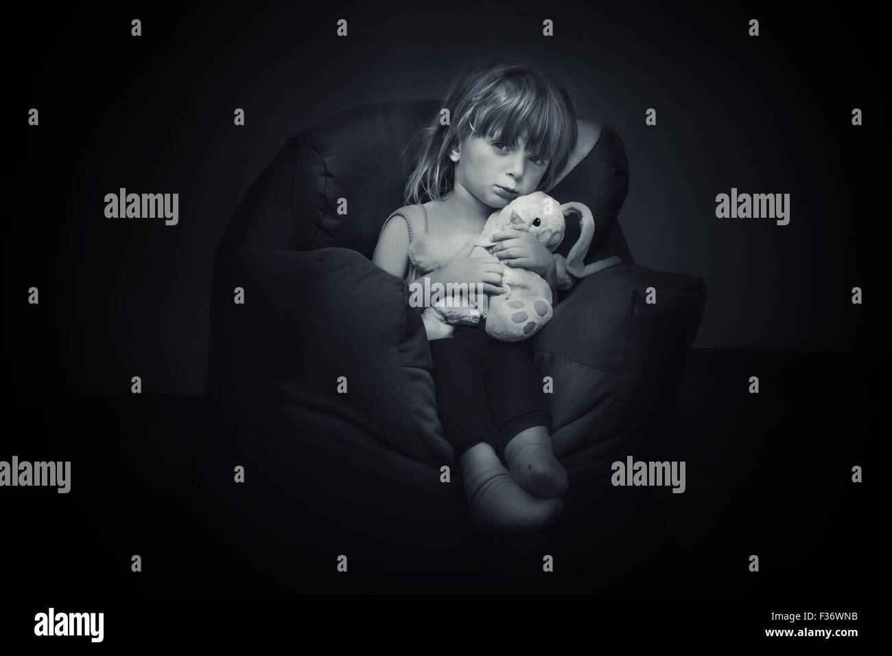 Triste ragazza seduta cuddling un giocattolo morbido. Foto Stock