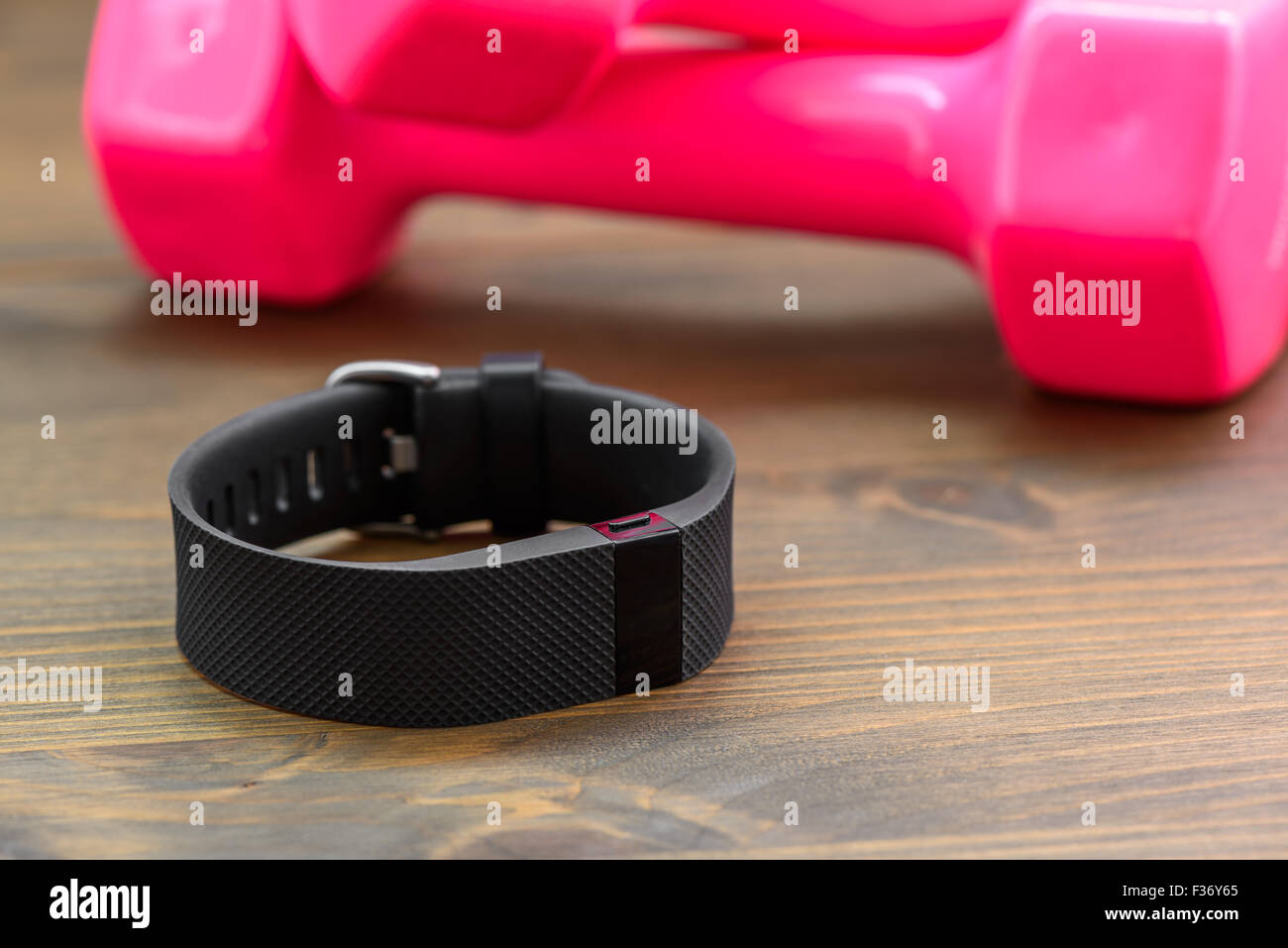 Dispositivo indossabile, wirst watch tipo Sport Tracker e rosa dumb-bell su una tavola di legno Foto Stock