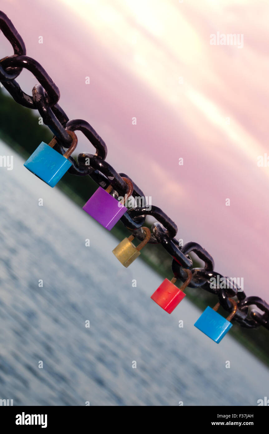 Diversi lucchetti colorati appesi da una catena di nero Foto Stock