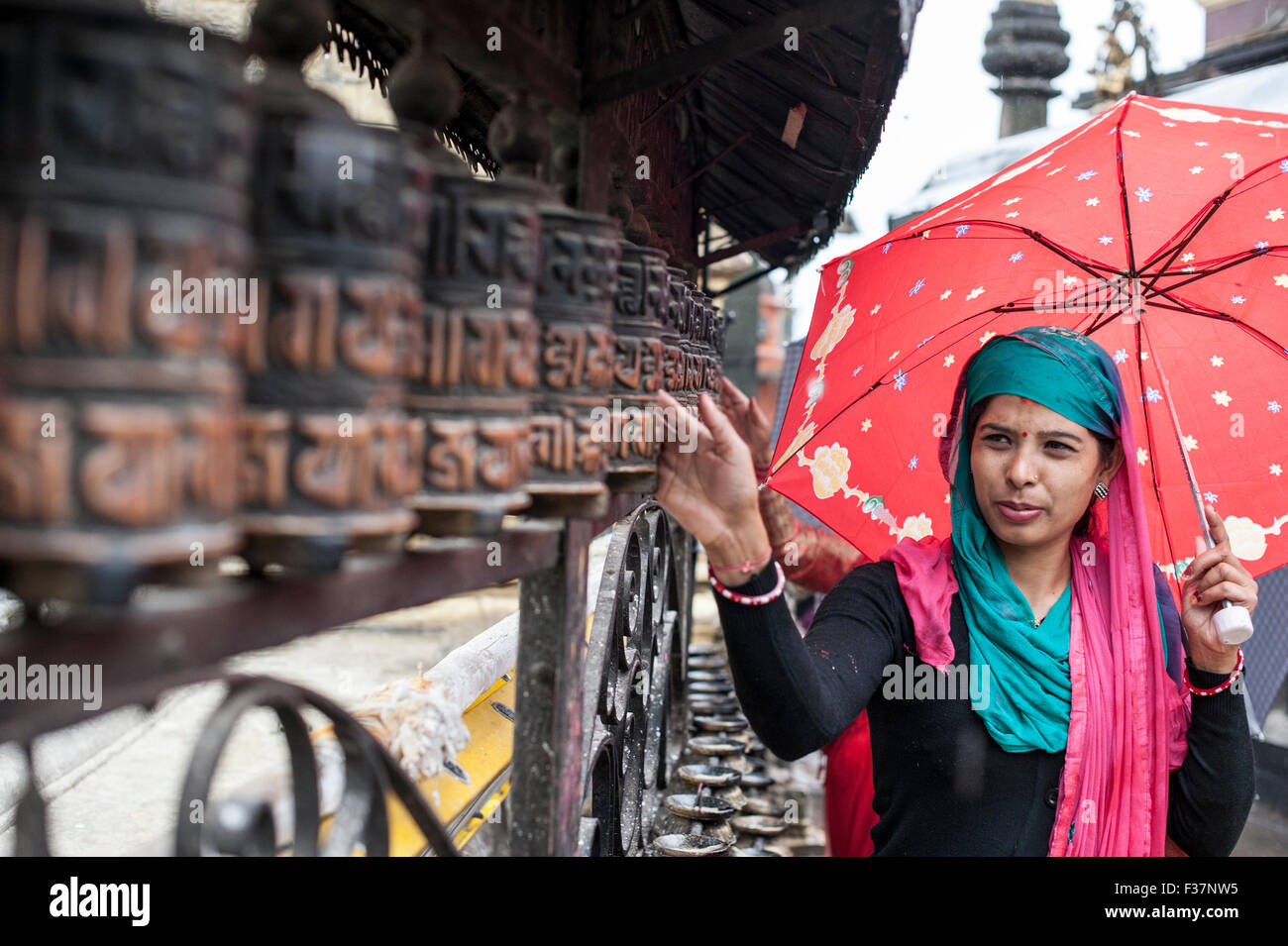 Una signora pregando con pregare wheles a Swayambhunath temple Kathmandu, Nepal Foto Stock