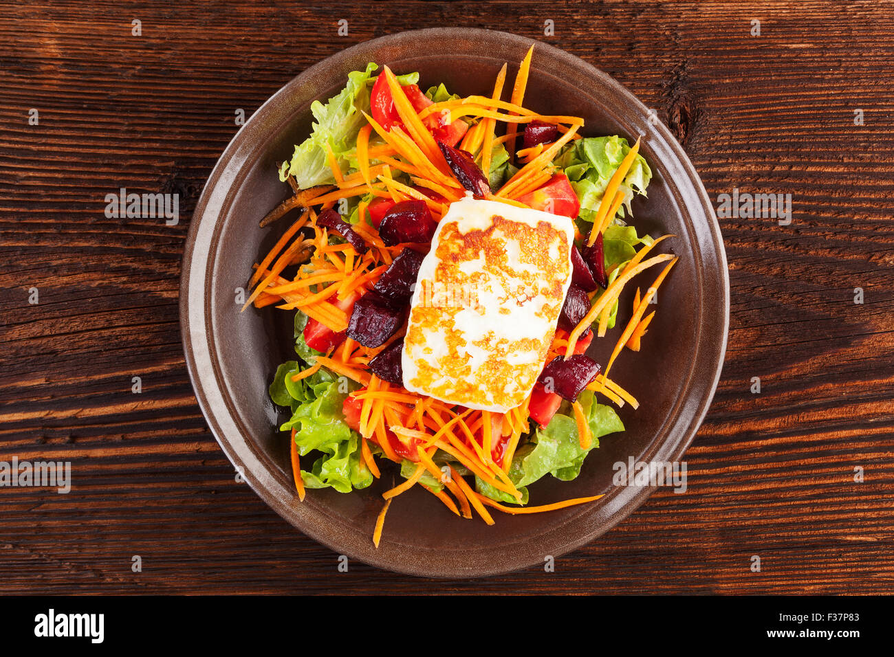 Grigliata di formaggio halloumi con colorati insalata fresca sulla piastra su un tavolo di legno, vista dall'alto. Prelibatezze deliziose mangiare vegetariano Foto Stock