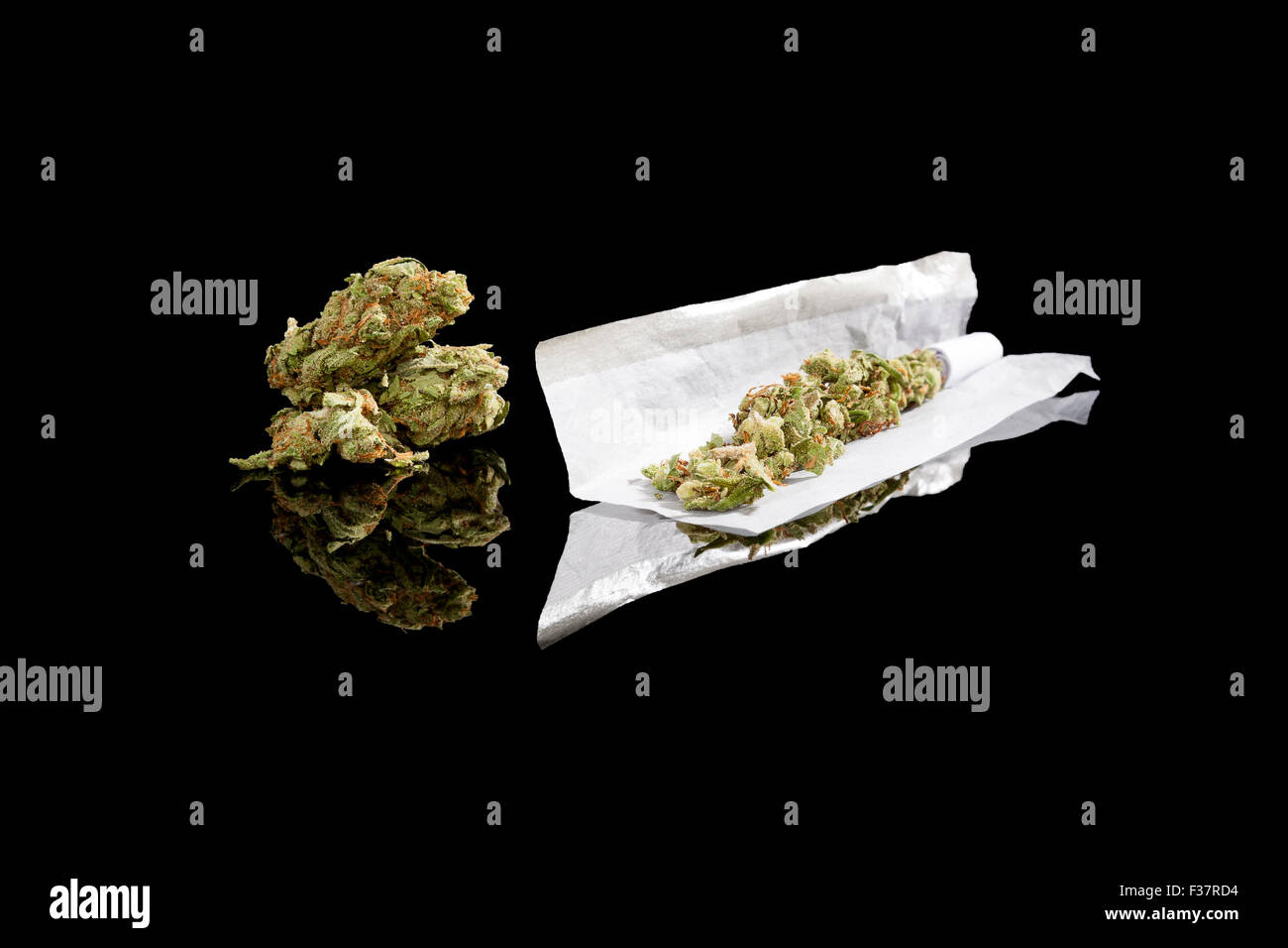 La marijuana bud e di sigarette di carta di rotolamento isolati su sfondo nero. Fumare cannabis, tossicodipendenza o uso medico. Foto Stock