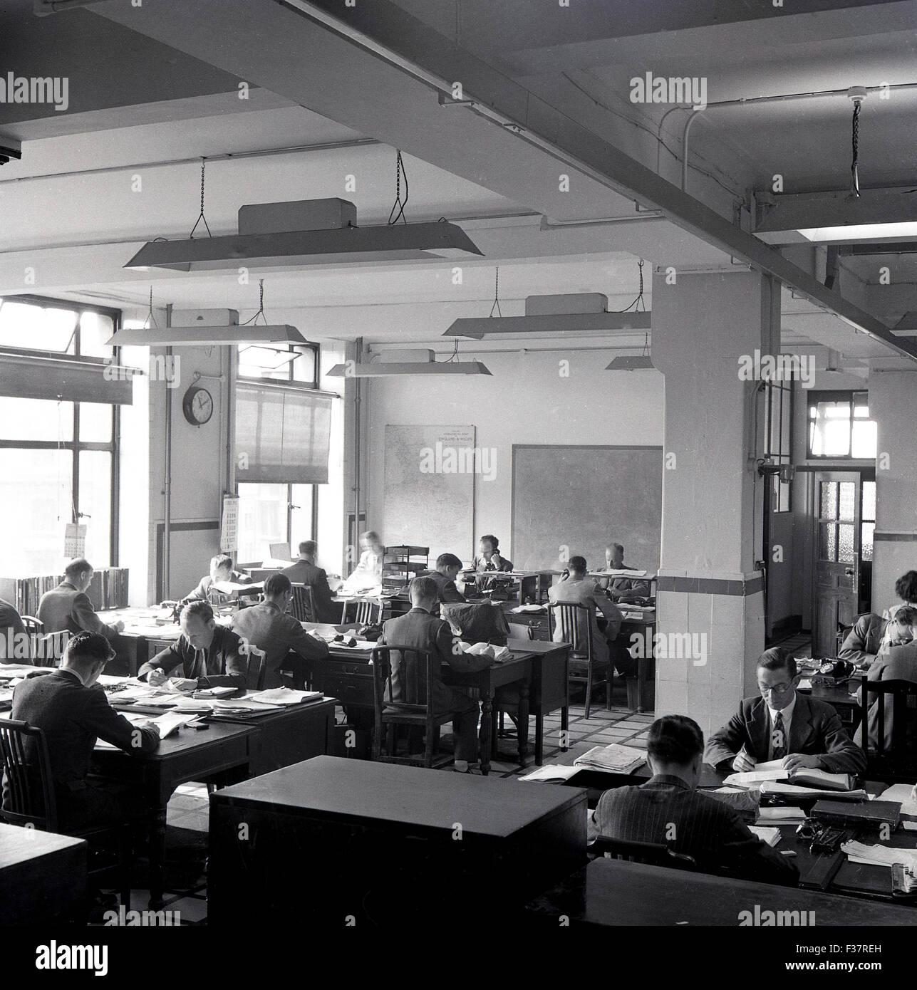 Storico degli anni cinquanta, un'immagine raffigurante un ufficio open space con personale di scrivanie unite insieme facendo il lavoro amministrativo. Foto Stock