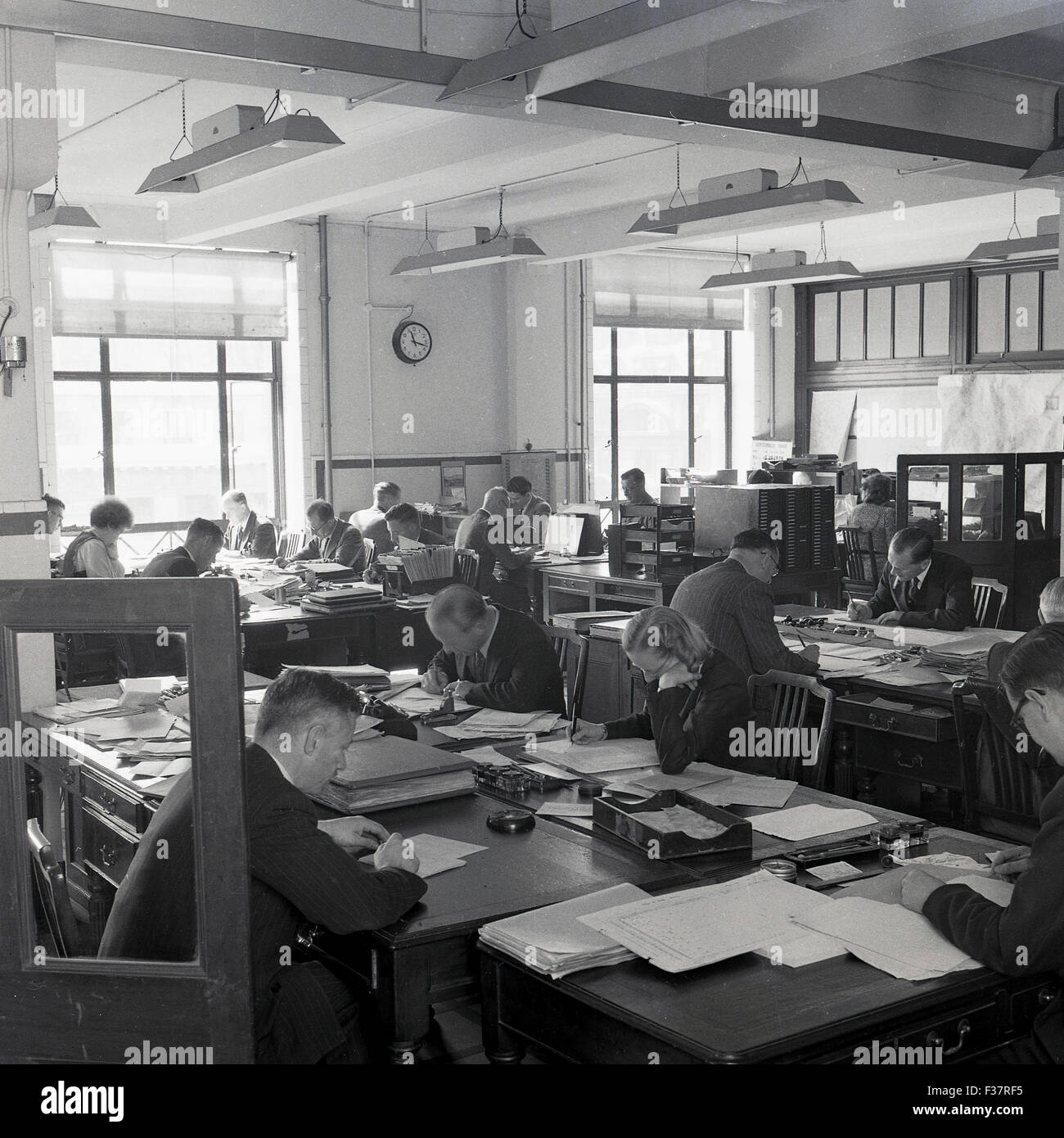 Storico degli anni cinquanta, un'immagine raffigurante un ufficio open space con personale di scrivanie unite insieme facendo il lavoro amministrativo. Foto Stock