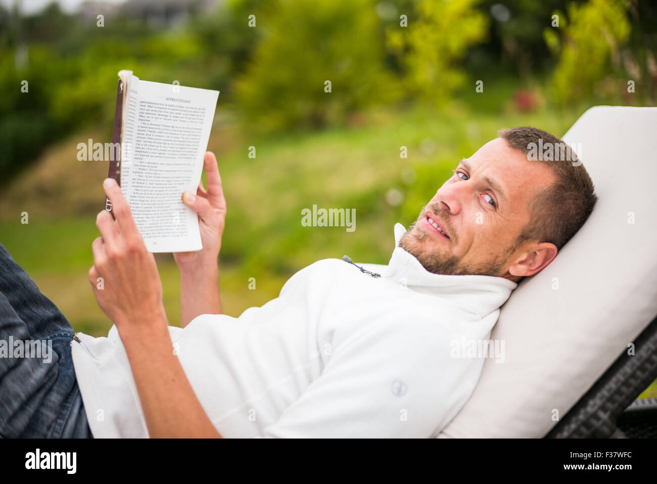 L'uomo la lettura di un libro in poltrona lounge all'aperto. Foto Stock