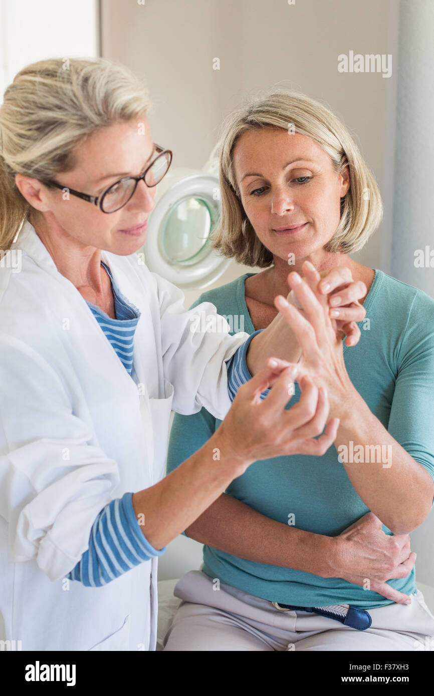 Medico esaminando la mano di un paziente. Foto Stock