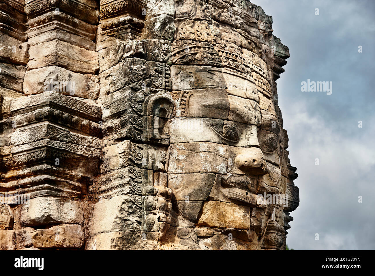 Gigantesco volto in pietra intagliato presso l'antico tempio di Bayon. Parco Archeologico di Angkor, Provincia di Siem Reap, Cambogia. Foto Stock