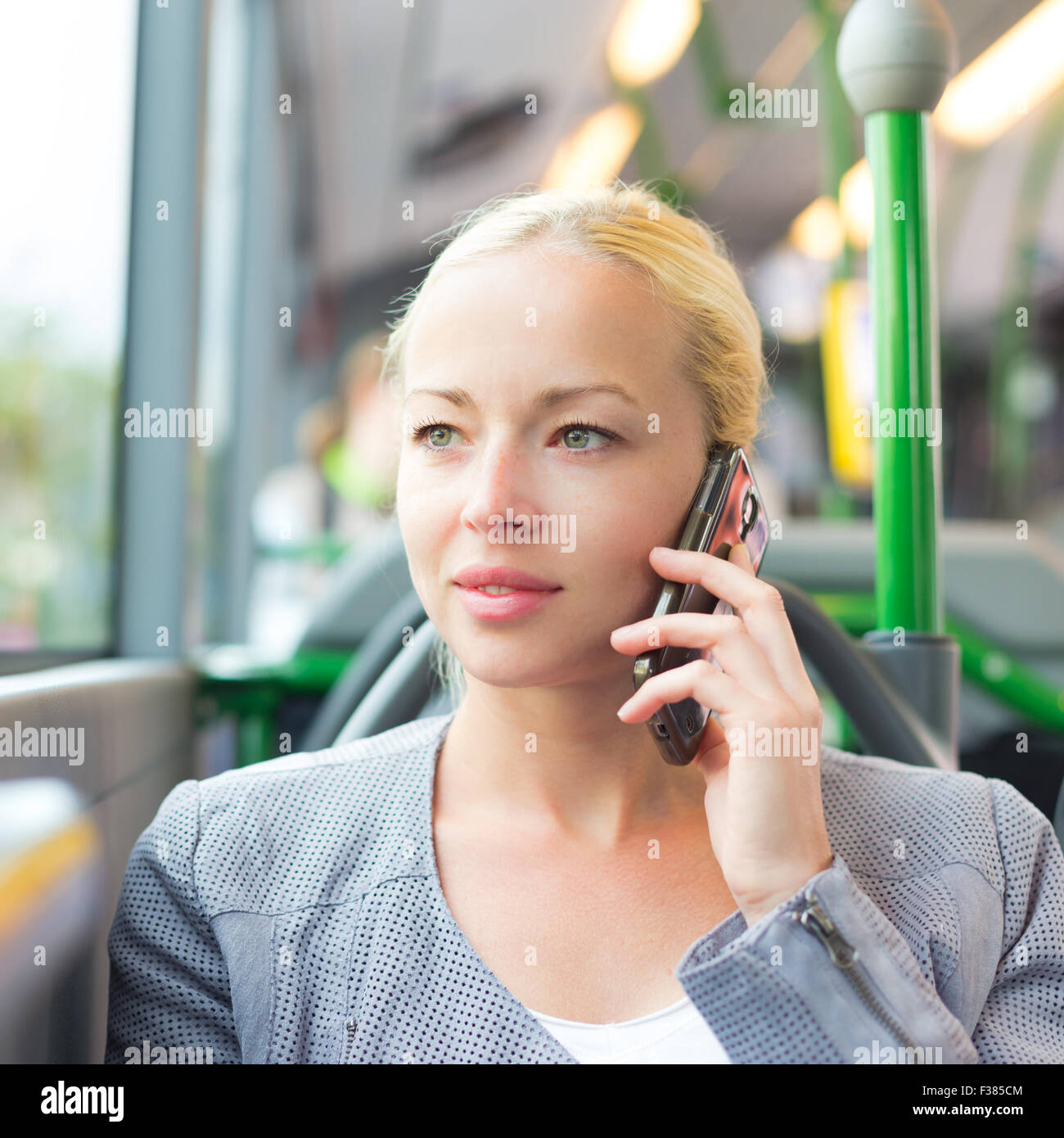 Bionda caucasica donna business parlando al cellulare per viaggiare in autobus. Il trasporto pubblico e il pendolarismo per lavoro. Foto Stock