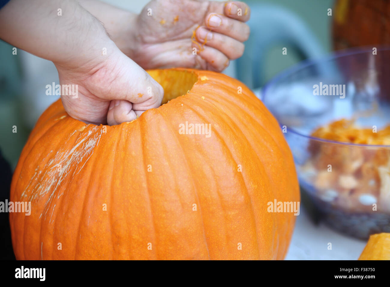 Un uomo tira le sementi e materiale fibroso da una zucca prima della scultura per la festa di Halloween. Foto Stock
