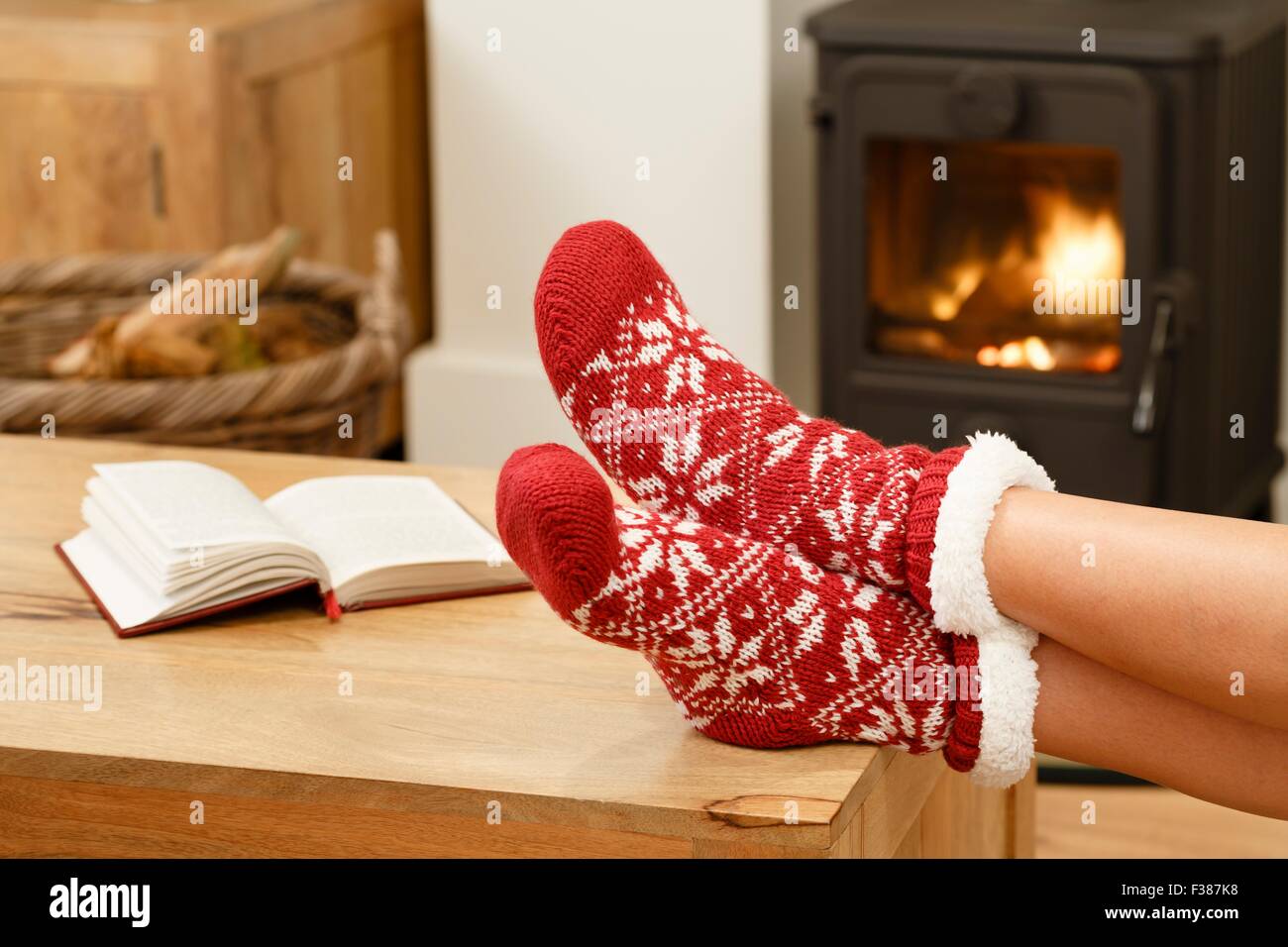 Donna in calze di Natale rilassante accanto a una stufa a legna Foto Stock