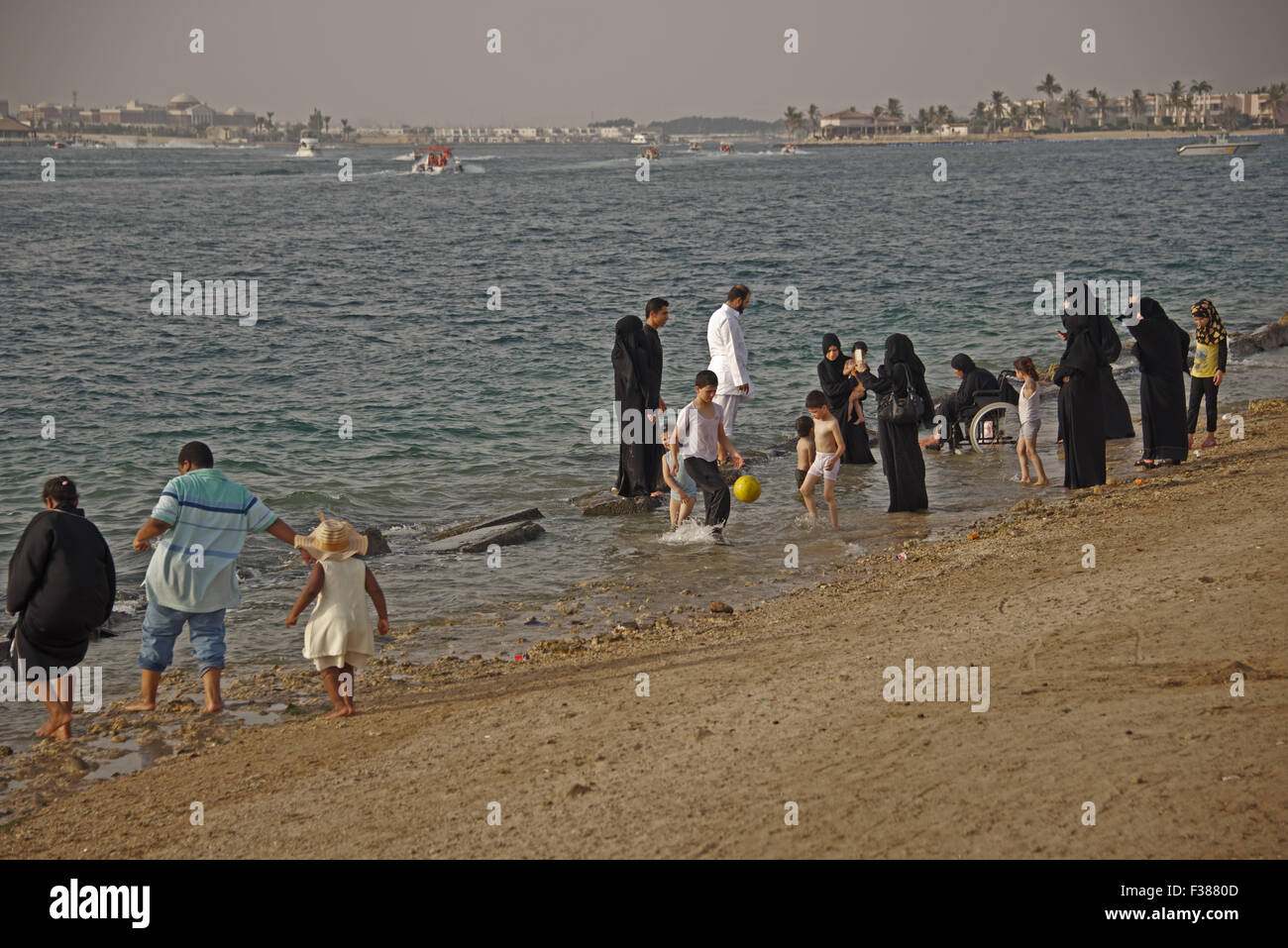 Una tipica scena presso la Corniche a Jeddah, Arabia Saudita. Famiglie passeggiare sulla spiaggia del Mar Rosso, pregare e guardare il tramonto Foto Stock