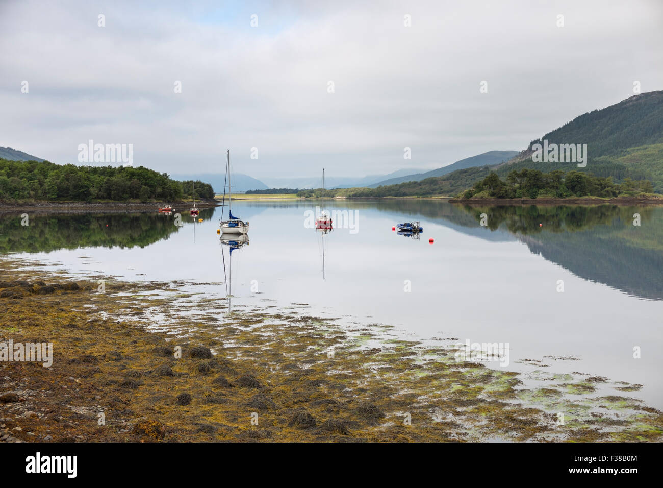 Barche ormeggiate su una calma piatta Loch Leven. Foto Stock