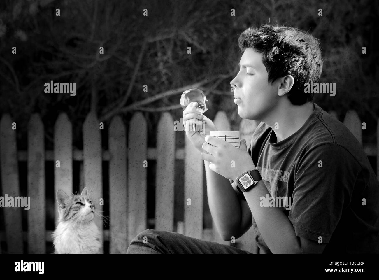 Ragazzo soffiando una bolla mentre il cat guarda a lui in bianco e nero simpatico momento Foto Stock