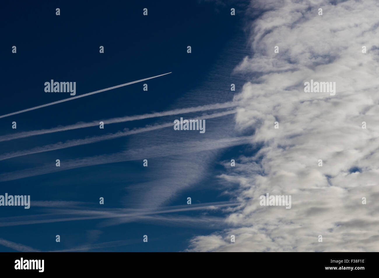 Resti di aerei sentieri di vapore nel cielo blu chiaro con un getto la rotta del velivolo per nubi di vapore uscente prova dietro di esso. Foto Stock
