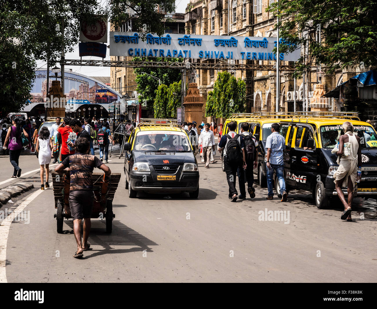 Scena cittadina, traffico, negozi, persone di fronte Chhatrapati Shivaji Terminus (vecchio: stazione ferroviaria Victoria) Foto Stock