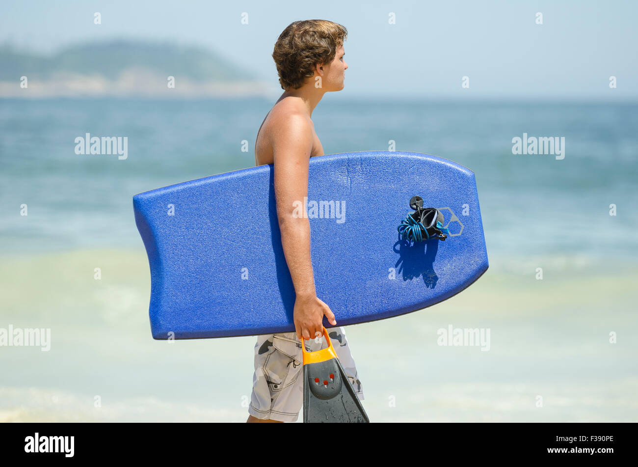 RIO DE JANEIRO, Brasile - 20 febbraio 2014: giovane brasiliano surfer passeggiate con scheda corpo lungo la riva della spiaggia di Ipanema. Foto Stock