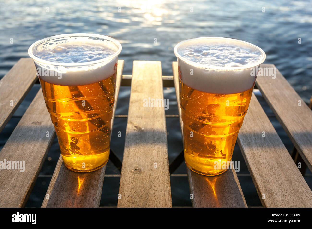 Birra ceca in tazze di plastica su un tavolo di legno sul fiume, tramonto a Praga romantica coppia Moldava a Praga Foto Stock