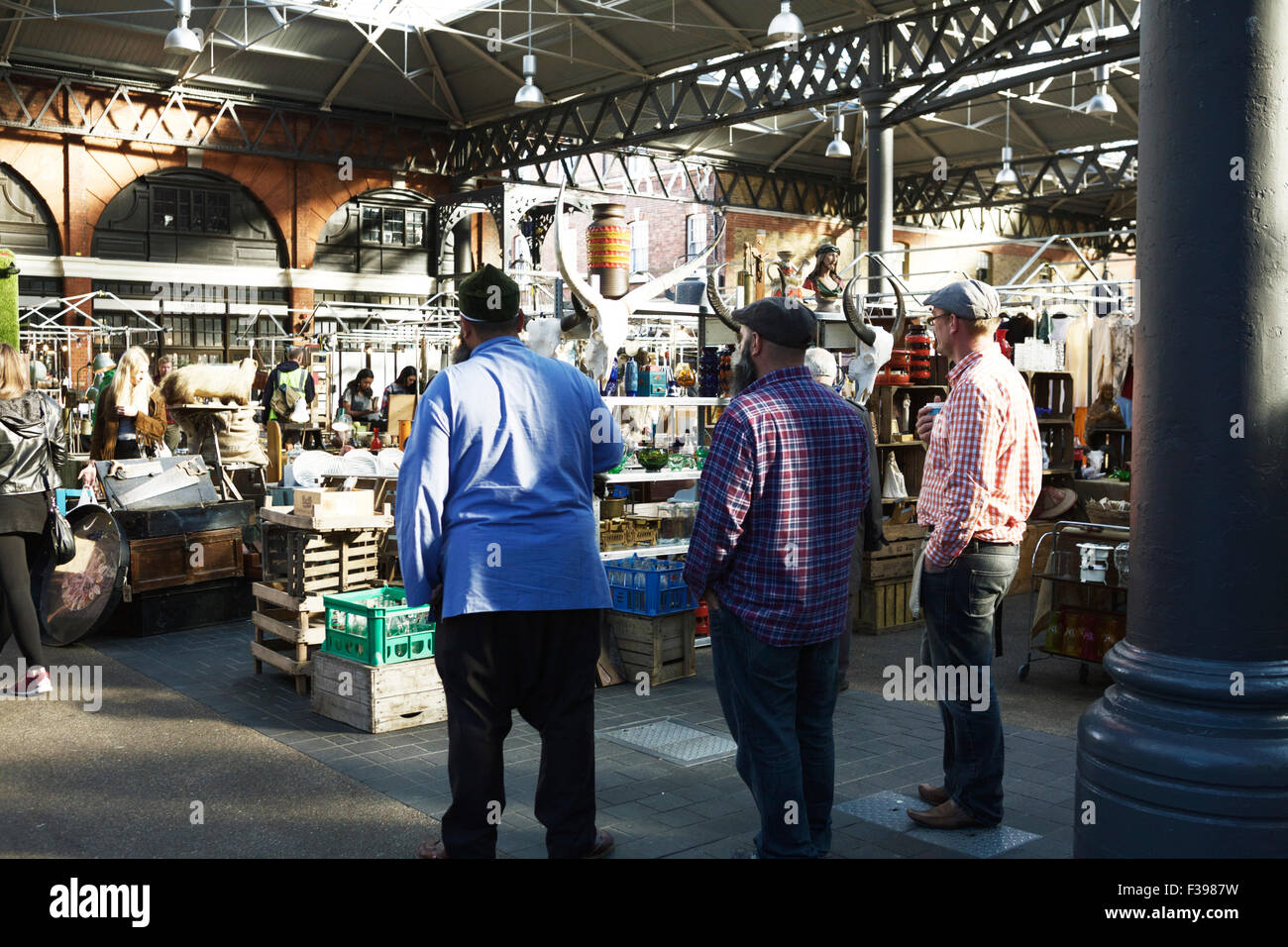 Il mercato di antiquariato al giorno, a Spitalfields Market di Londra, Inghilterra, Regno Unito. Gli operatori di mercato a guardare i clienti. Foto Stock