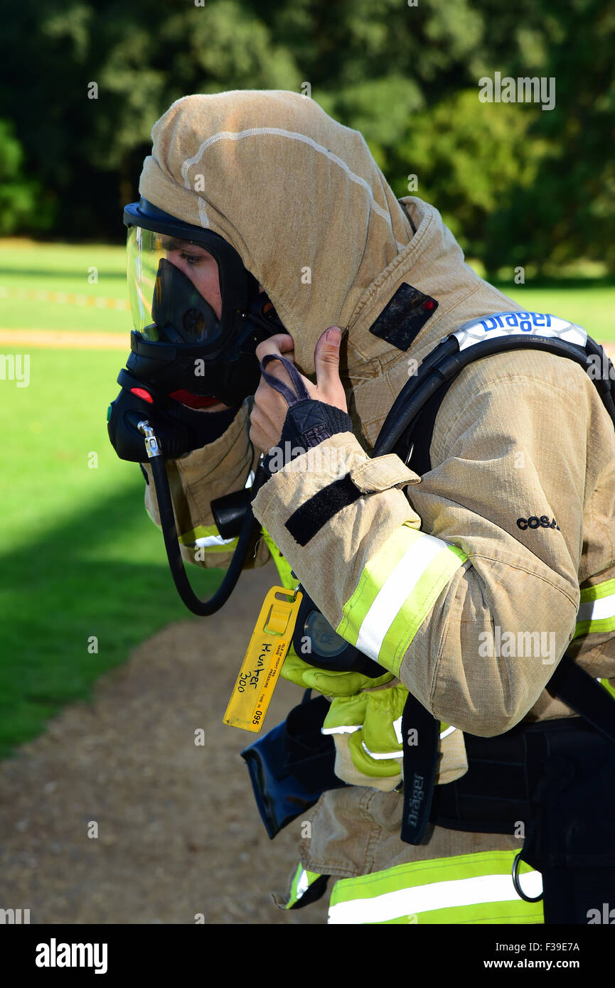 Firefighter prepara il suo apparato di respirazione, controllo della sua guarnizione di tenuta, sulla scena di un incendio. Foto Stock