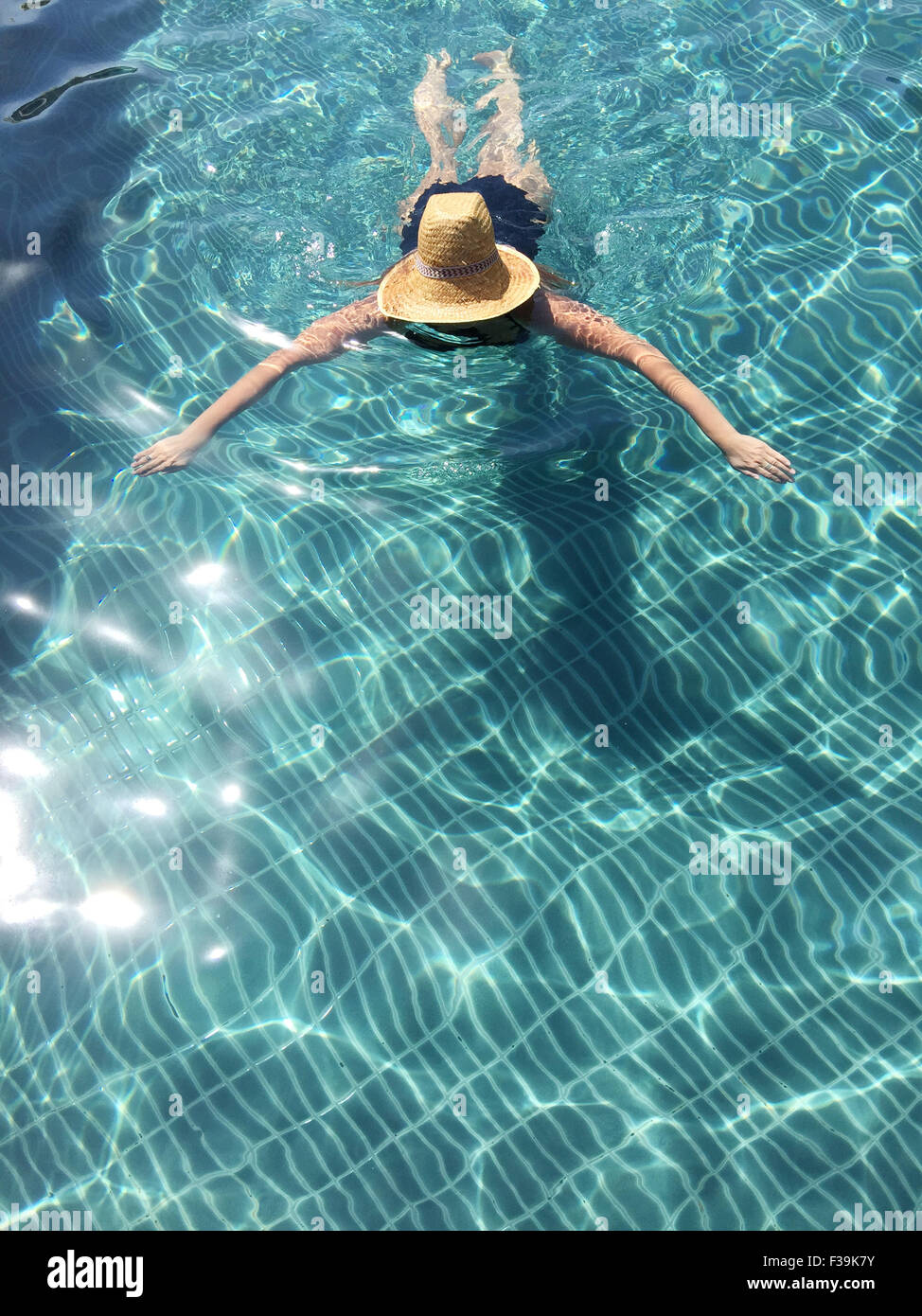 Donna che indossa un cappello di paglia che nuota in una piscina, Thailandia Foto Stock