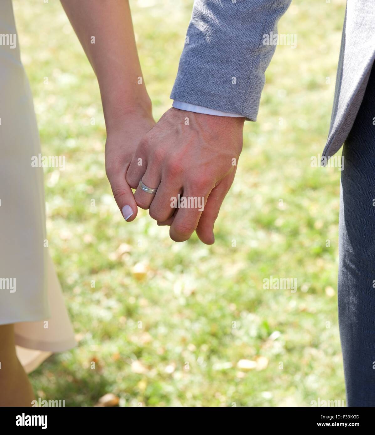 Close-up di una sposa e lo sposo tenendo le mani al loro matrimonio Foto Stock