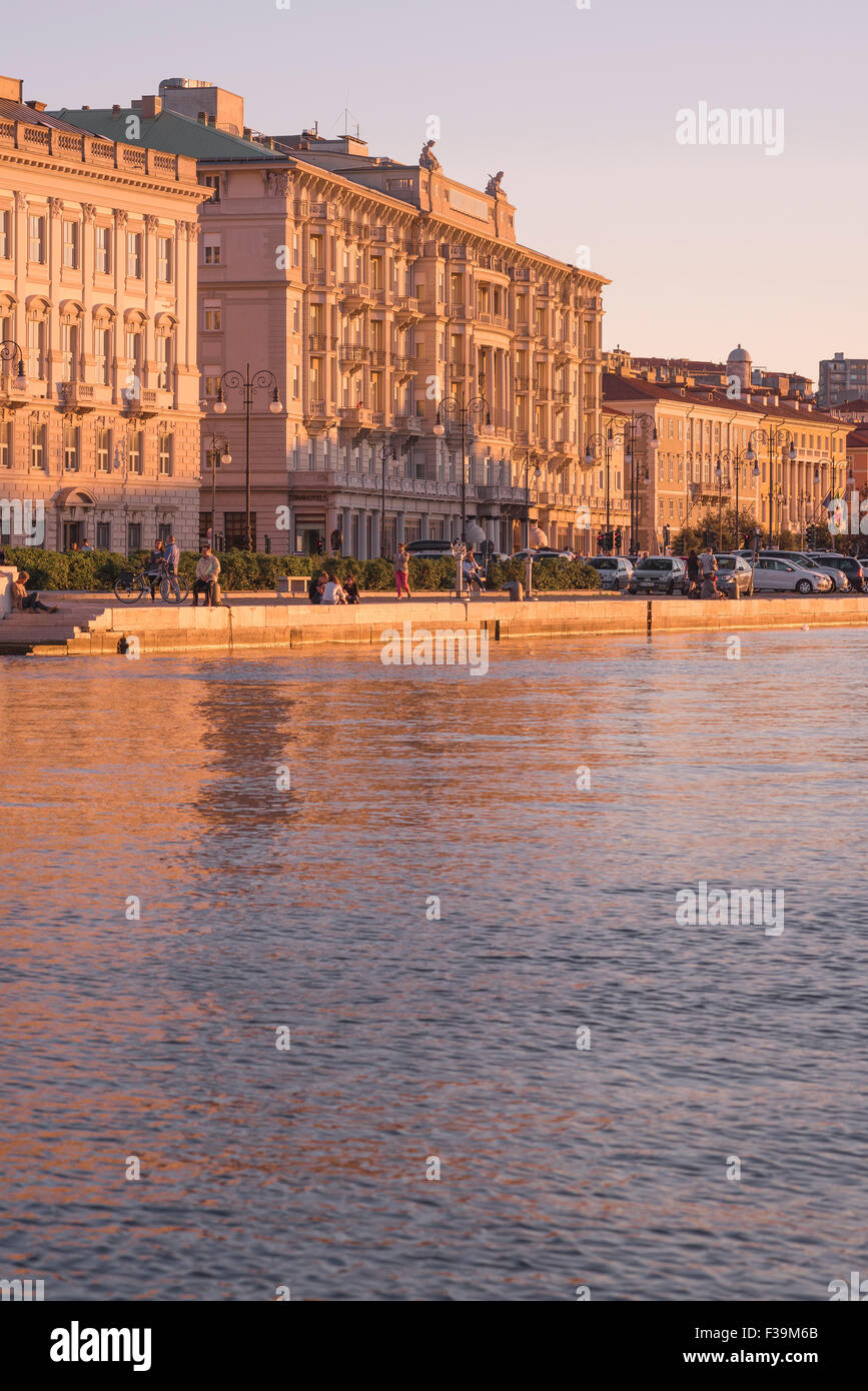 Tramonto sul porto di Trieste, vista degli edifici lungo la Riva del Madraccchio nella zona centrale del lungomare di Trieste Foto Stock