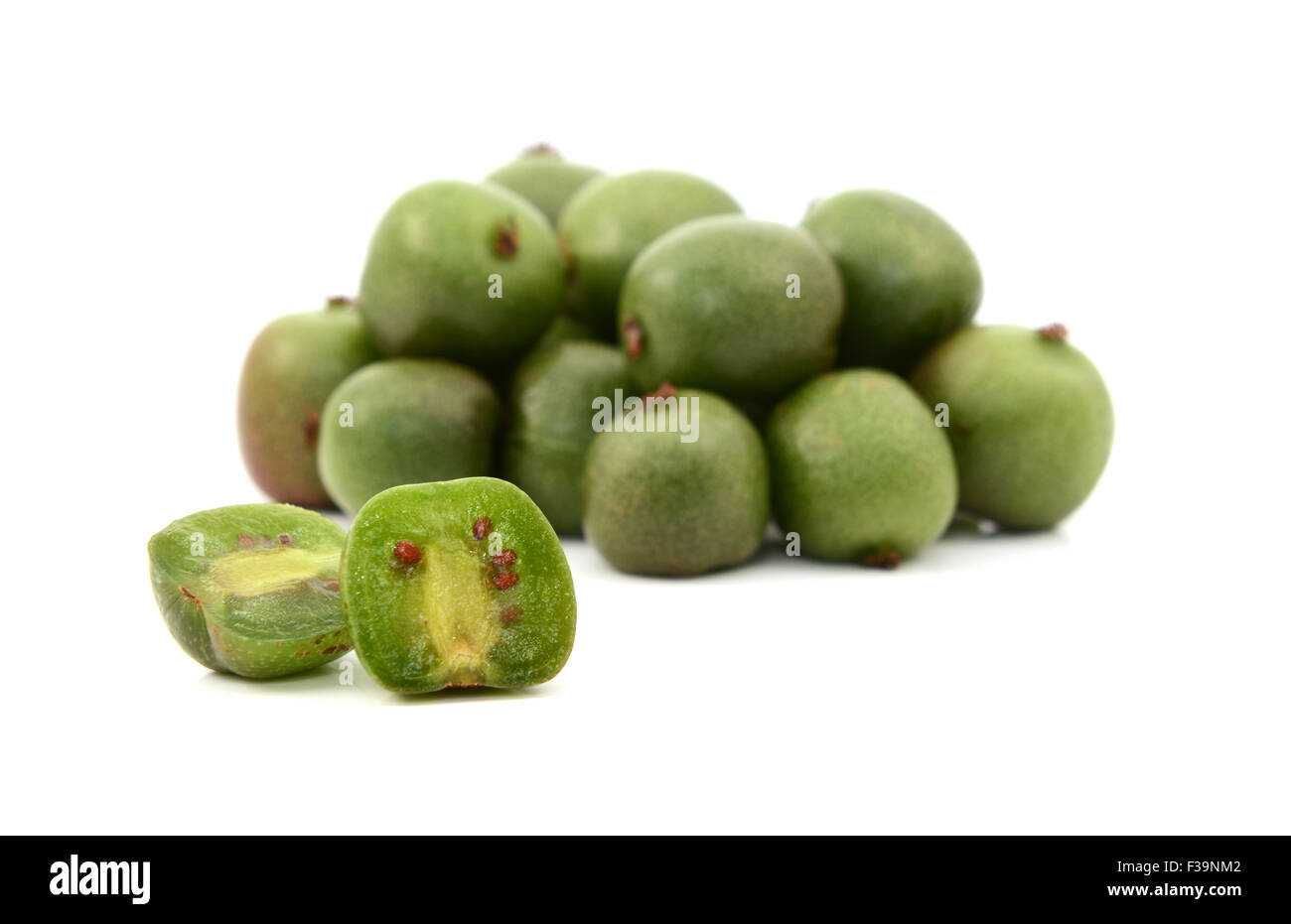 Un kiwi berry affettato aperto nella parte anteriore della pila di bacche, isolato su uno sfondo bianco Foto Stock