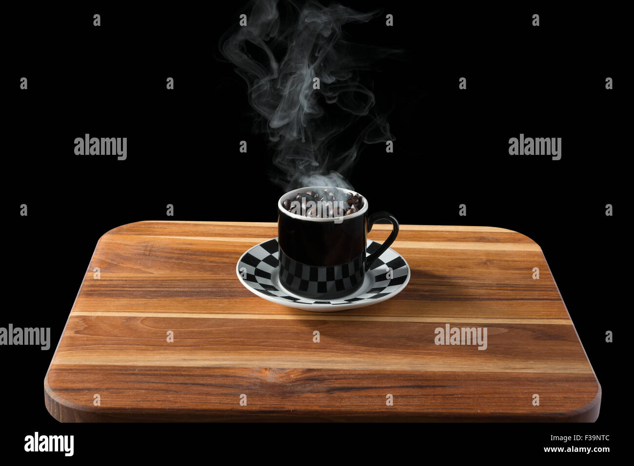 Tazza di caffè sul piattino voluta con la tostatura i chicchi di caffè sul tagliere di legno su uno sfondo nero. Foto Stock