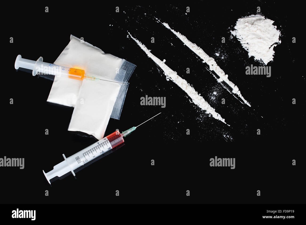 La cocaina e le siringhe su sfondo nero Foto Stock