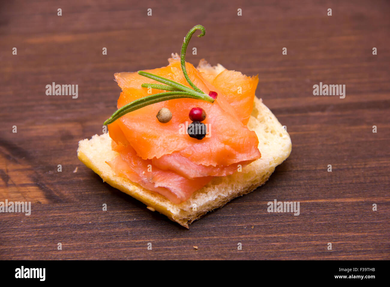 Salmone affumicato su fette di pane abbrustolito sul tavolo di legno Foto Stock