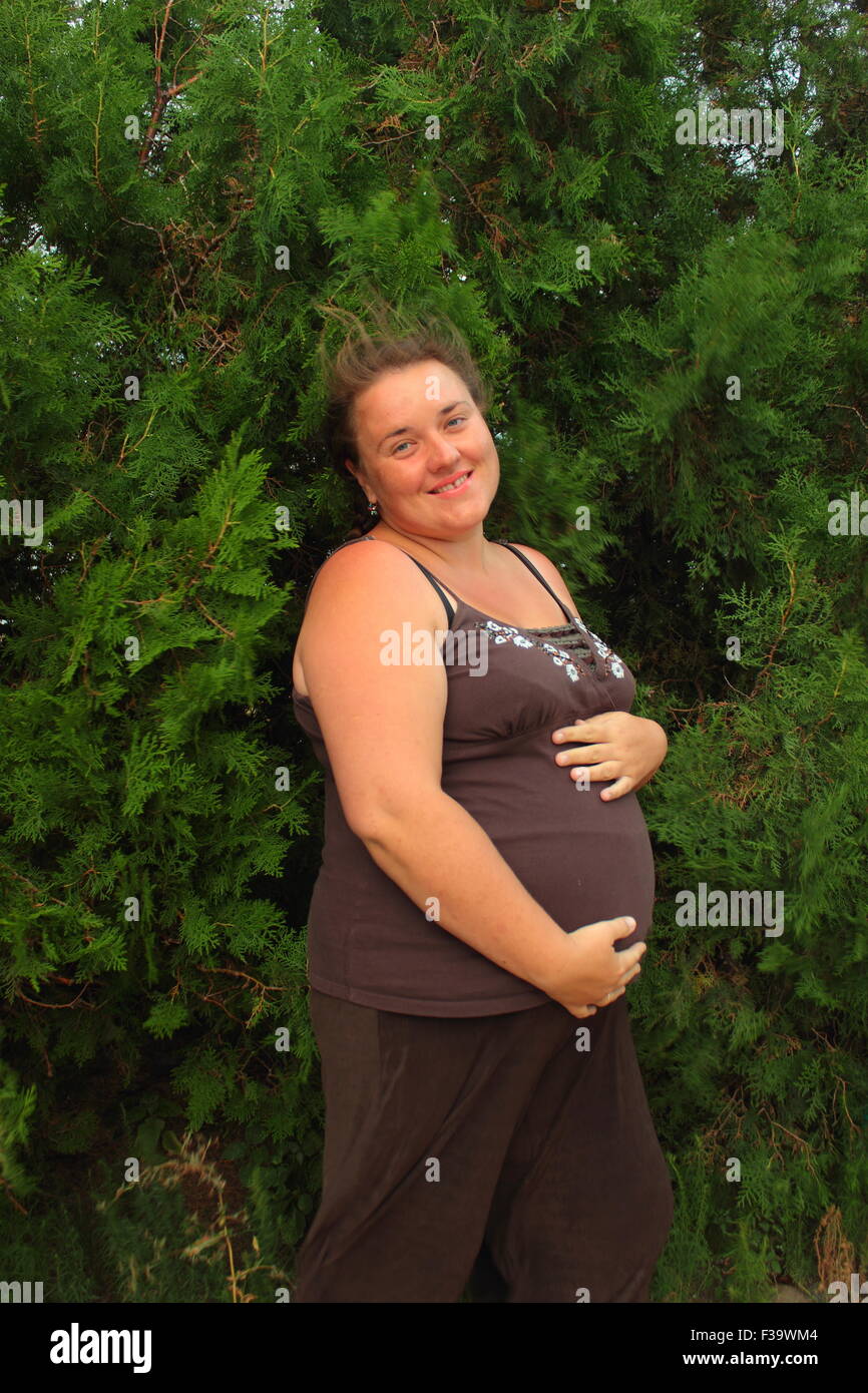 Felice donna incinta sullo sfondo di abeti Foto Stock