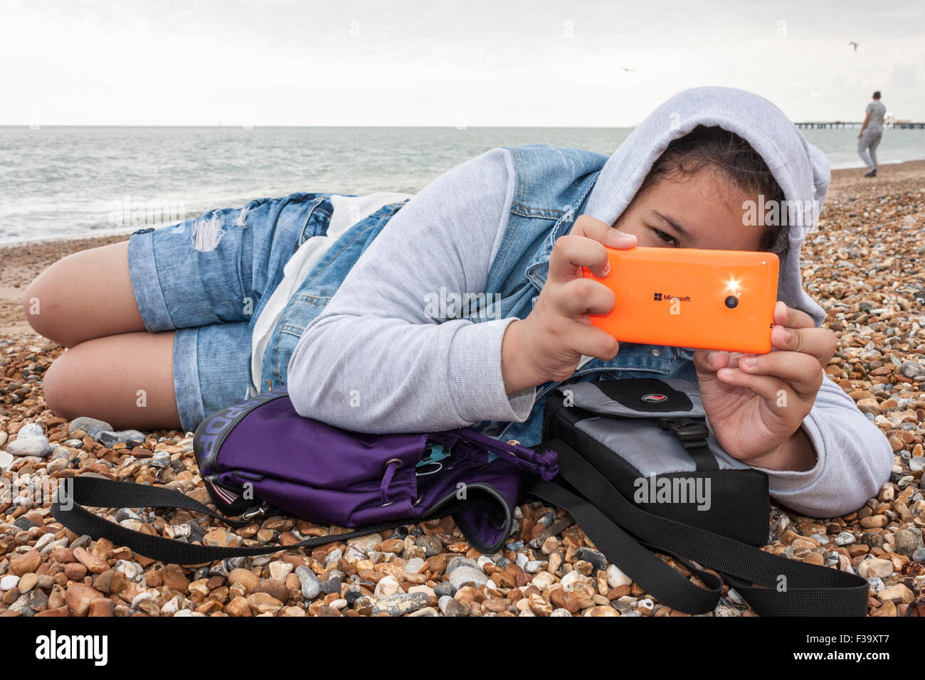 Ragazza adolescente prende foto con flash utilizzando il telefono cellulare. Foto Stock