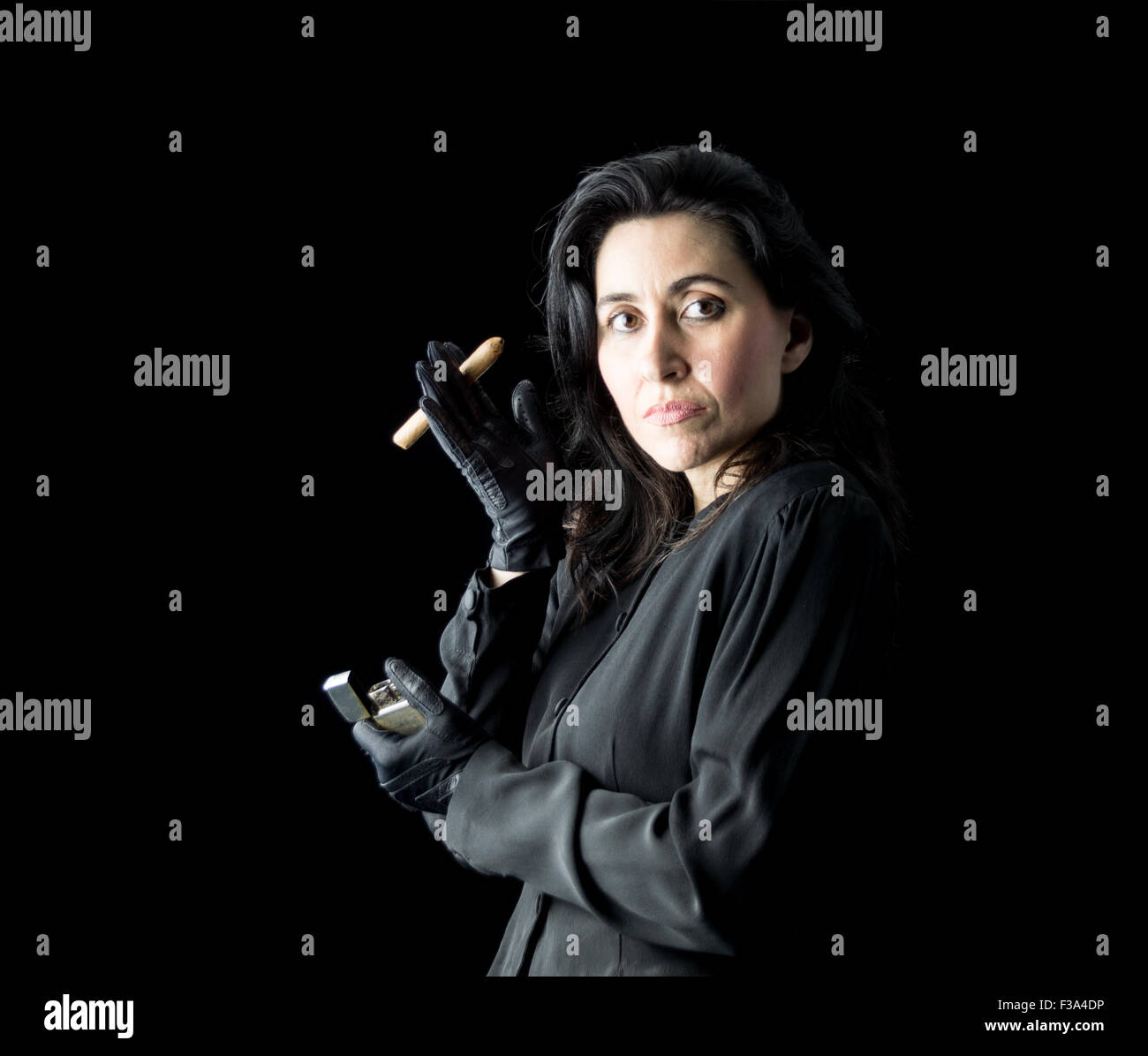 Brunette donna in abito nero e guanti neri tenendo un sigaro in una mano e un accendino in altri Foto Stock