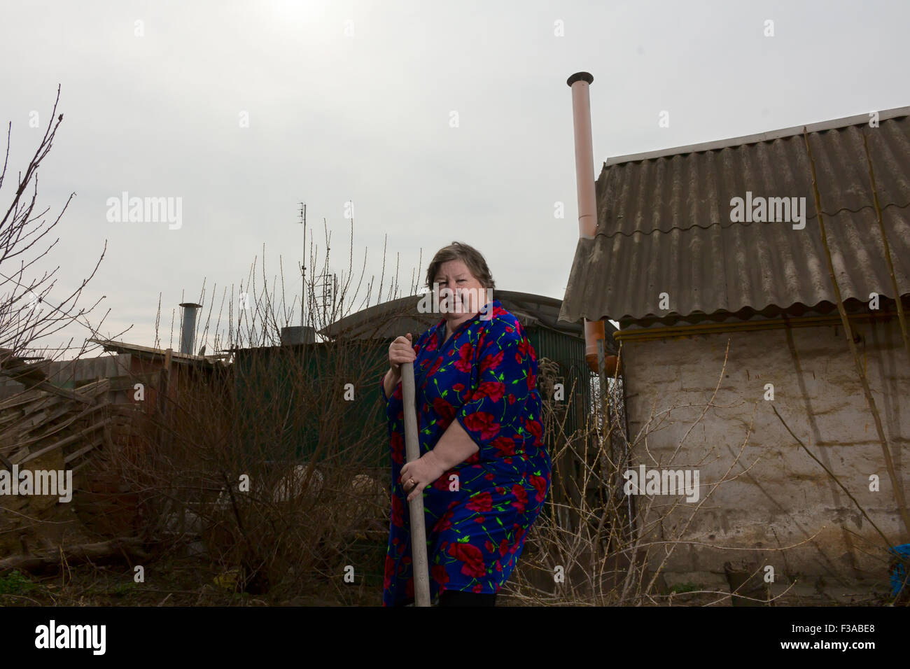 Una donna anziana con una pala, giardino coltivato. Foto Stock