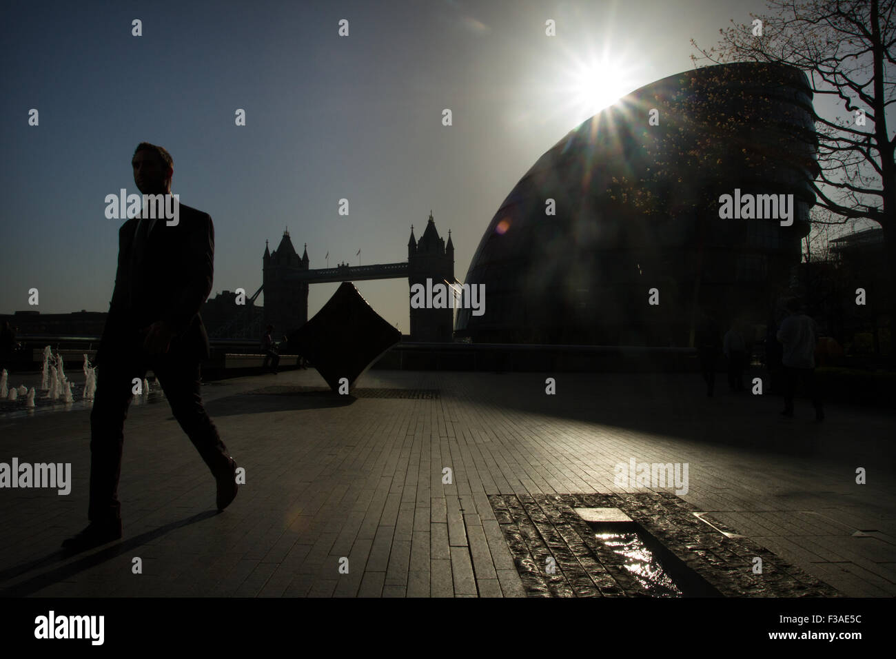 Un uomo silhouette silhouette vicino al Municipio di Londra e al Tower Bridge a sfondo Foto Stock