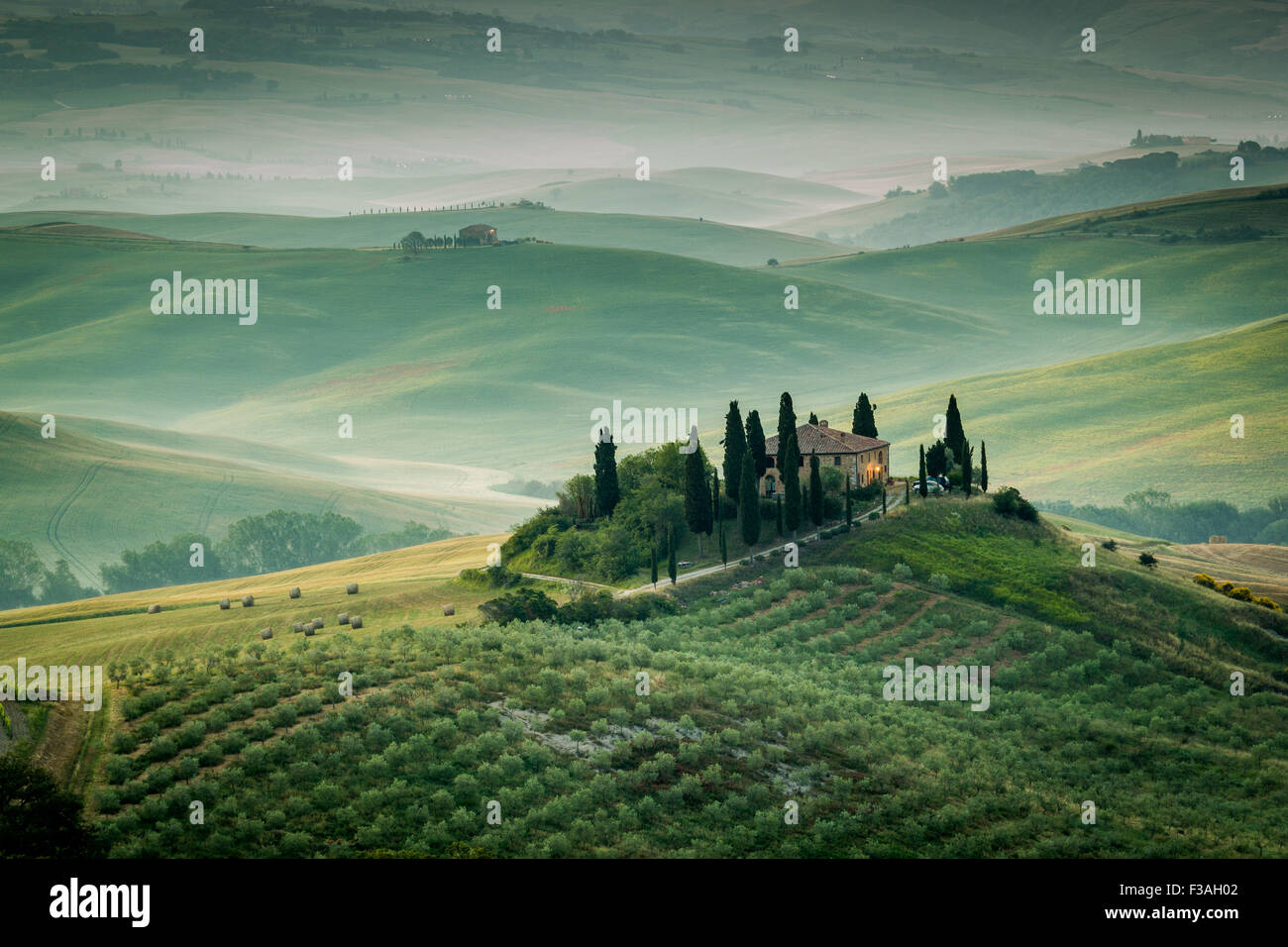Toscana, agriturismo solitario nel verde e golden paese delle colline della Val d'Orcia, la mattina presto. Paesaggio italiano. Foto Stock