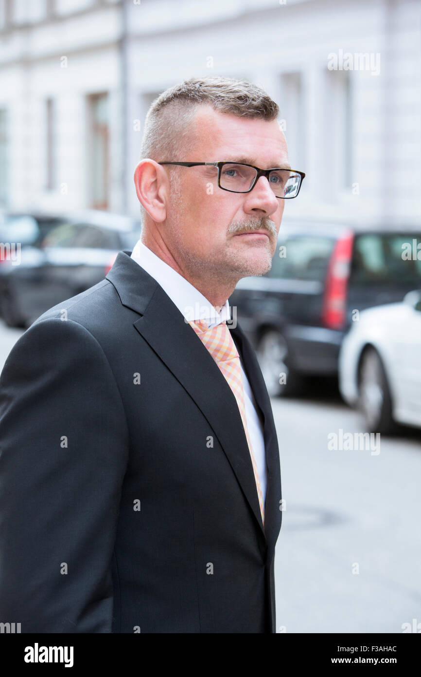 Ritratto di imprenditore in piedi in strada con gli occhiali Foto Stock