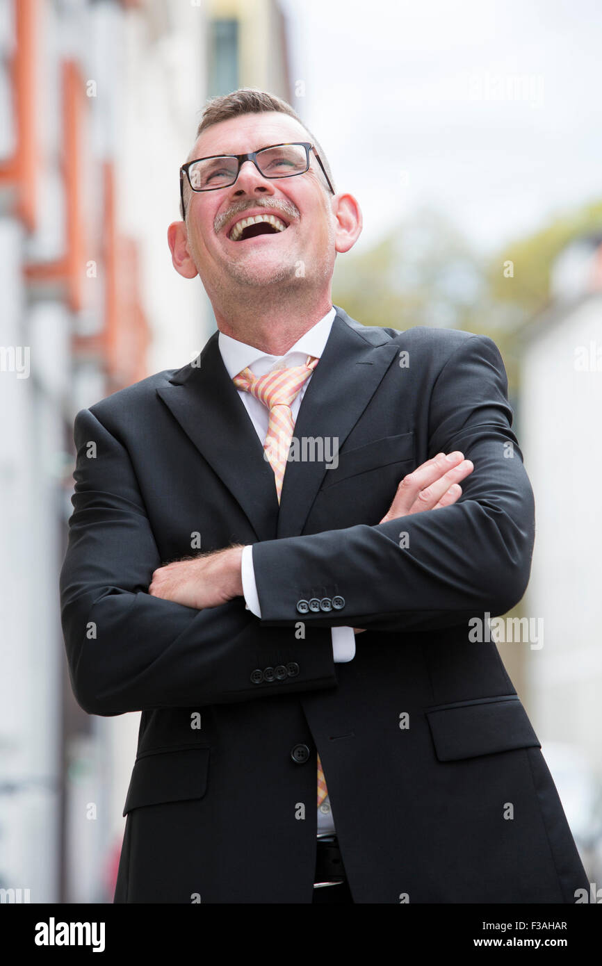 Ritratto di imprenditore in piedi in strada e ridere Foto Stock