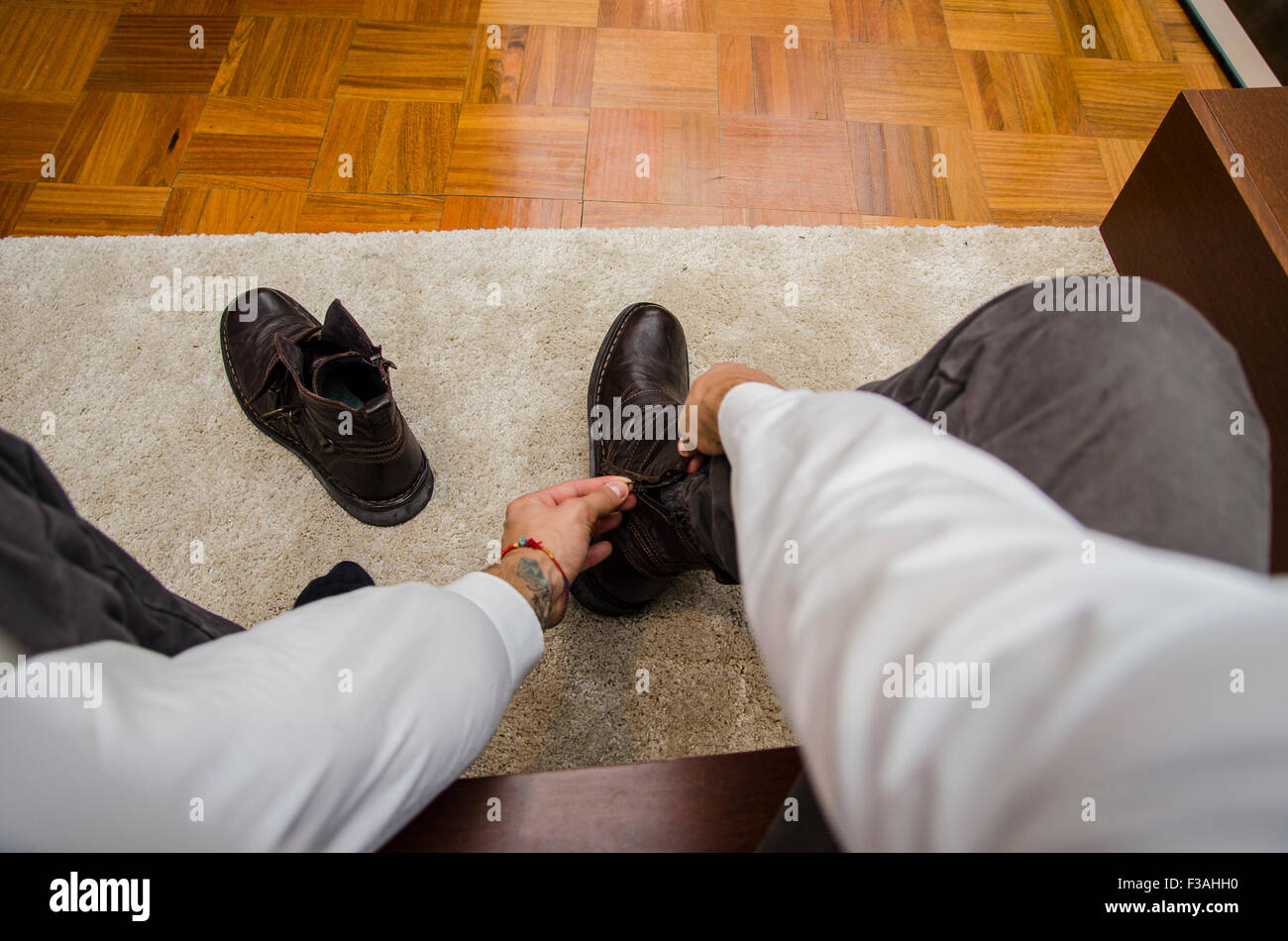 Medicazione di uomo seduto su una sedia la piegatura verso il basso la sua legatura lacci della scarpa, prima persona il punto di vista. Auto POV Foto Stock