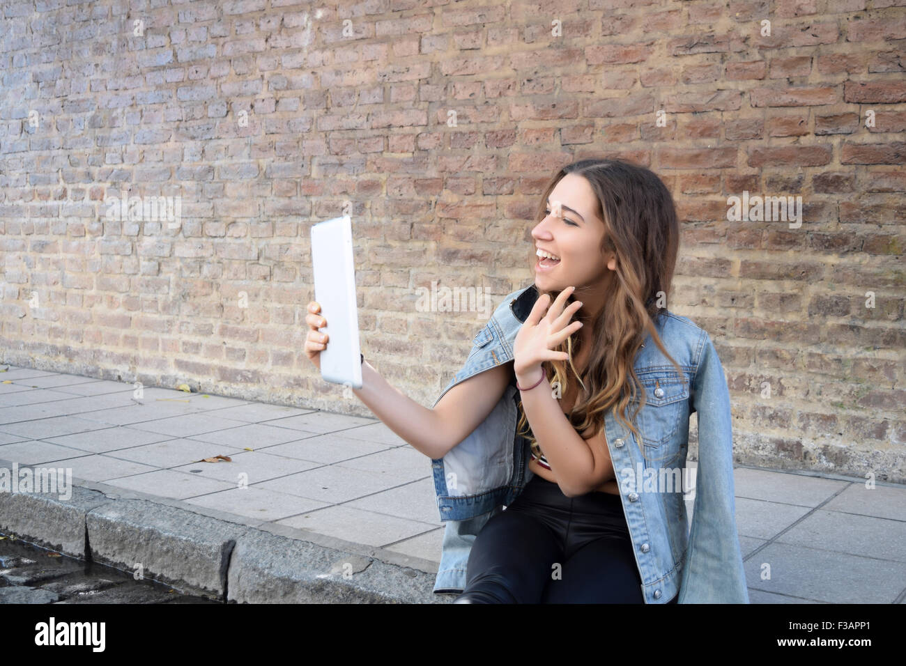 Giovane donna ispanica utilizzando una compressa sulla strada. Moda e stile urbano. Foto Stock